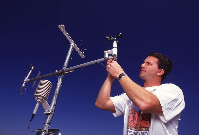 A field technician adjusting a weather station mast